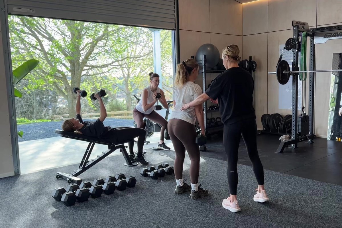 Kate coaching dumbbell work with the roller door open to the trees